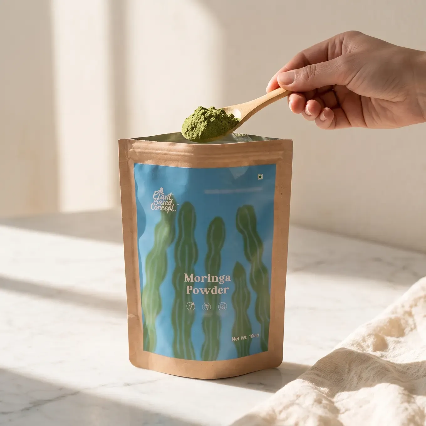 A wooden spoonful of moringa powder scooped from the pouch